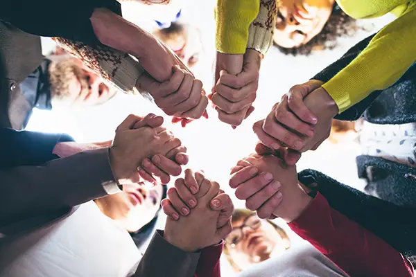 Diverse hands joined in a circle with fists together, signaling teamwork and solidarity.